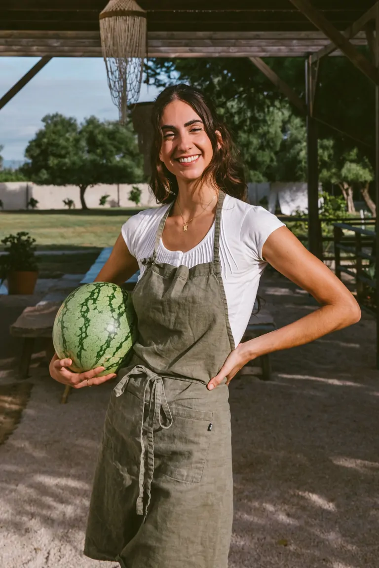 Laia, a chef & Permaculture designer, smiles while holding a watermelon at Suniai Oliva.